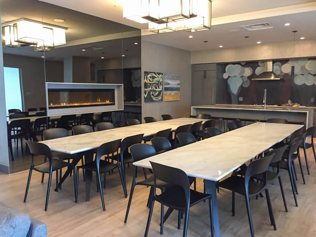 Open dining and kitchen area with modern decor, white countertops, and black chairs. - 1105 - 125 E 14th St, North Vancouver