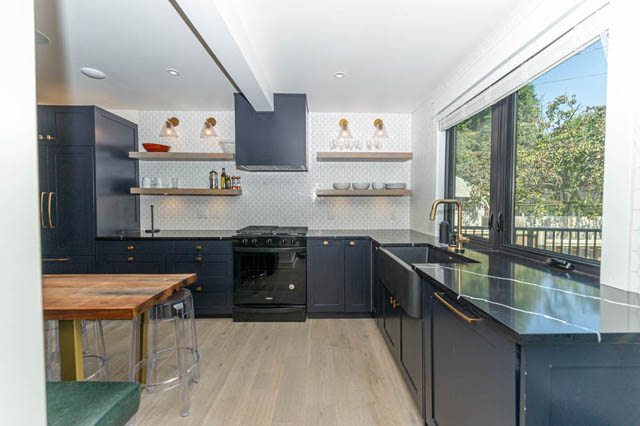 Bright kitchen with dark cabinetry, open shelving, and a city view through large windows. - MAIN SUITE - 730 Hawks Ave, Vancouver East Side