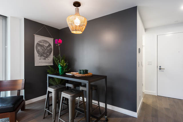 Furnished dining area with dark walls, wooden table, and hanging light fixture. - 1901 - 1480 Howe St, Vancouver Downtown