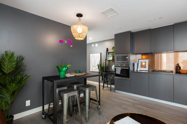 Furnished kitchen with dark cabinets, wooden countertops, and a modern chandelier. - 1901 - 1480 Howe St, Vancouver Downtown
