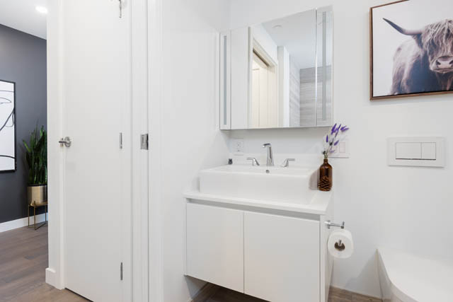 Bright bathroom with white cabinetry and modern sink, hardwood floors. - 1901 - 1480 Howe St, Vancouver Downtown