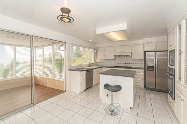 Bright kitchen with white cabinetry, stainless steel appliances, and tiled floor. - 669 Eyremount Drive, West Vancouver