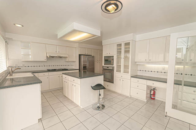 Bright kitchen with white cabinets, granite countertops, and stainless steel appliances. - 669 Eyremount Drive, West Vancouver