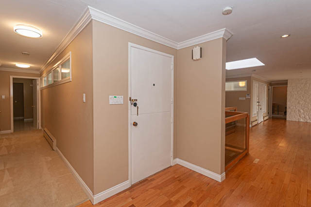 Bright hallway with hardwood floors and white trim, leading to a door and another room. - 669 Eyremount Drive, West Vancouver