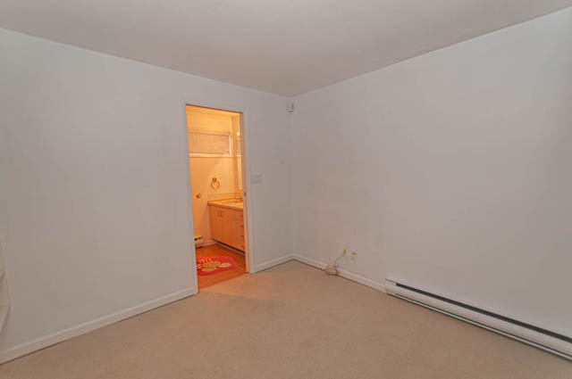 Bright bedroom with white walls and carpeted floor, leading to a lit hallway. - 669 Eyremount Drive, West Vancouver