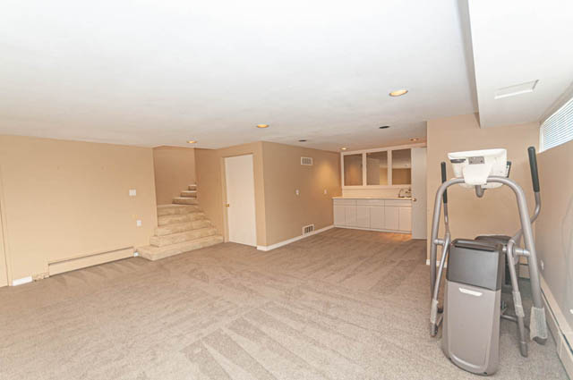 Bright living room with beige walls and hardwood floors, featuring a treadmill and exercise equipment. - 669 Eyremount Drive, West Vancouver