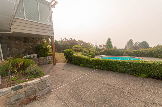 Furnished backyard with stone walls, manicured hedges, and a pool. - 669 Eyremount Drive, West Vancouver