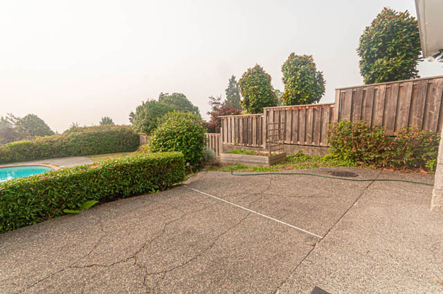 Furnished patio with stone flooring, hedge border, and wooden fence. - 669 Eyremount Drive, West Vancouver