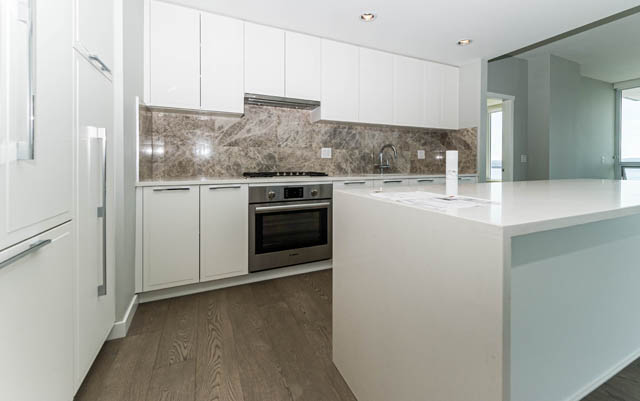 Bright kitchen with white cabinets, marble backsplash, and hardwood floors. - 802 - 118 Carrie Cates Court, North Vancouver