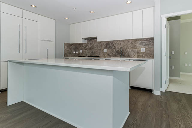 Bright kitchen with white cabinetry, granite countertops, and hardwood floors. - 802 - 118 Carrie Cates Court, North Vancouver