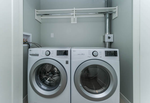 Laundry room with stacked washer and dryer, white shelves above. - 802 - 118 Carrie Cates Court, North Vancouver