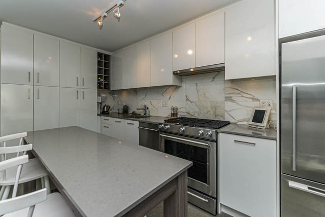 Bright kitchen with white cabinets, marble backsplash, and stainless steel appliances. - 501 - 231 E Pender Street, Vancouver Downtown