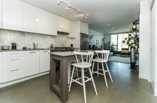 Bright kitchen with white cabinets, marble backsplash, and a city view. - 501 - 231 E Pender Street, Vancouver Downtown