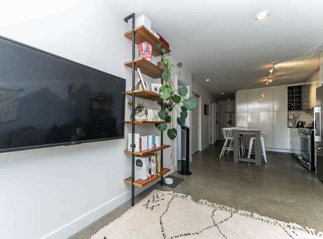 Bright living room with modern shelving, large TV, and cozy rug. - 501 - 231 E Pender Street, Vancouver Downtown