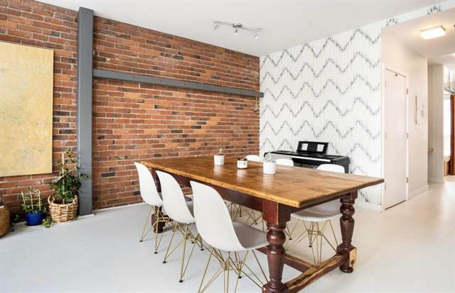 Furnished dining area with brick wall, wooden table, and modern chairs. - 410 - 1072 Hamilton St, Vancouver Downtown