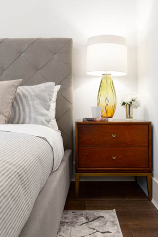 Furnished bedroom with a tufted headboard, wooden nightstand, and a vase of flowers. - 201 - 1785 W 16th Avenue, Vancouver West Side