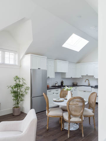 Bright kitchen with white cabinets, hardwood floors, and a skylight, perfect for a cozy dining area. - 3170 Burrard St, Vancouver West Side