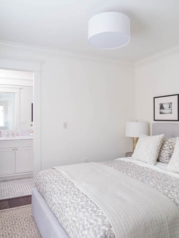 Furnished bedroom with white walls, patterned bedding, and a modern ceiling light. - 3170 Burrard St, Vancouver West Side