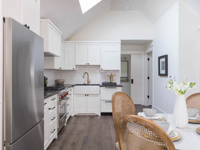 Bright kitchen with white cabinets, stainless steel appliances, and hardwood floors. - 3170 Burrard St, Vancouver West Side