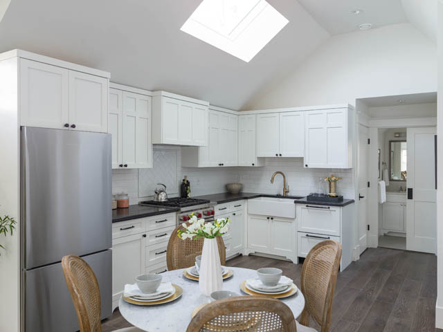 Bright kitchen with white cabinets, marble countertops, hardwood floors, and a skylight. - 3170 Burrard St, Vancouver West Side