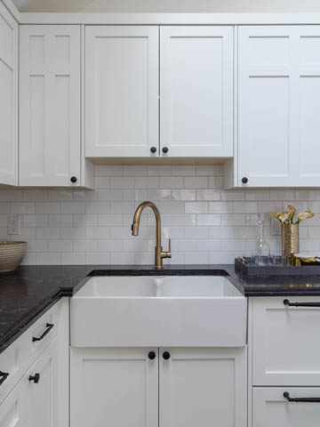 Bright kitchen with white cabinets, black countertops, and gold fixtures. - 3170 Burrard St, Vancouver West Side