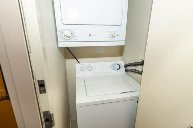 Bright laundry area with stacked washer and dryer, white countertops. - 1602 - 977 Mainland Street, Vancouver Downtown