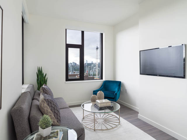 Bright living room with city view and modern decor, featuring a grey sofa and a glass coffee table. - 805 -  210 E 5th Avenue, Vancouver East Side