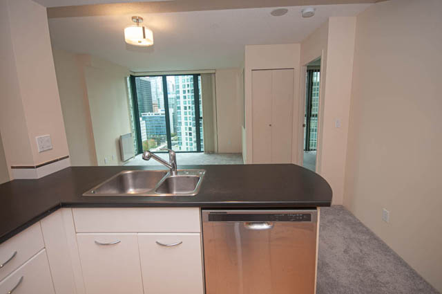 Bright kitchen with sleek black countertops, stainless steel sink, and city view. - 1801 - 1331 W Georgia St, Vancouver Downtown