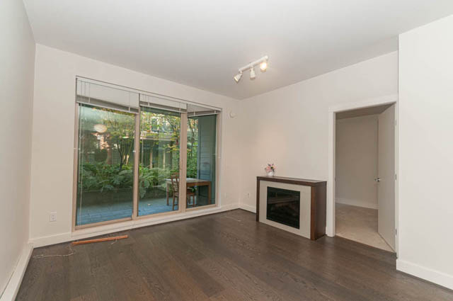 Spacious living room with hardwood floors and sliding glass doors leading to a private patio. - 117 - 3478 Westbrook Mall, Vancouver West Side