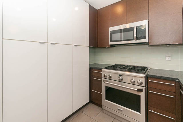 Bright kitchen with modern white cabinets, granite countertops, and stainless steel appliances. - 117 - 3478 Westbrook Mall, Vancouver West Side