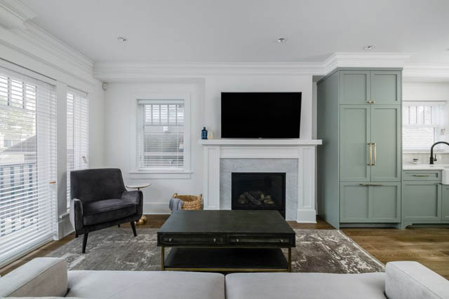 Bright living room with light green cabinets, hardwood floors, and a large TV above a fireplace. - 200 - 1775 W 16th Avenue, Vancouver West Side