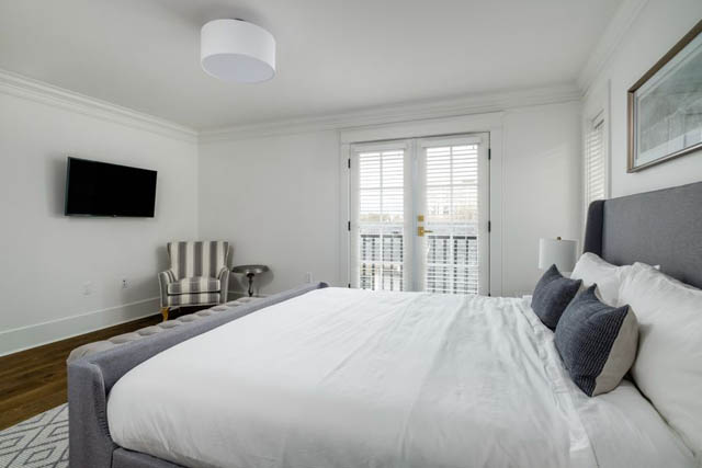 Bright bedroom with white walls, large windows, and a flat-screen TV mounted on the wall. - 200 - 1775 W 16th Avenue, Vancouver West Side