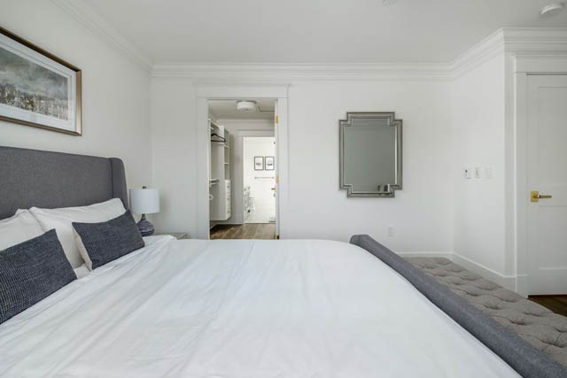 Bright and airy bedroom with white walls, a grey headboard, and a large mirror. - 200 - 1775 W 16th Avenue, Vancouver West Side