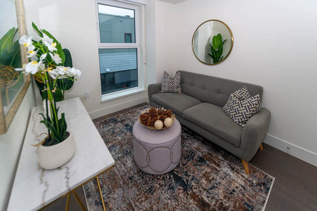 Spacious living room with marble countertops, a cozy gray sectional, and a large window offering a city view.