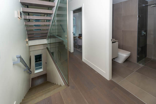 Modern townhouse entry with sleek hardwood floors, glass rail staircase, and contemporary bathroom. - 146 W Woodstock Ave, Vancouver West Side