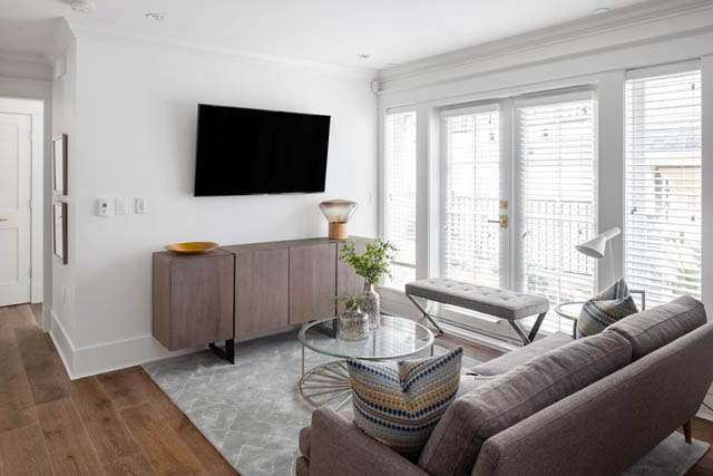 Bright living room with hardwood floors, large windows, and a modern TV setup. - 	1783 W 16th Ave, Vancouver West Side