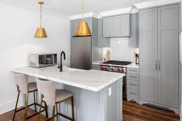 Bright kitchen with marble countertops, gray cabinets, and gold pendant lights. - 	1783 W 16th Ave, Vancouver West Side