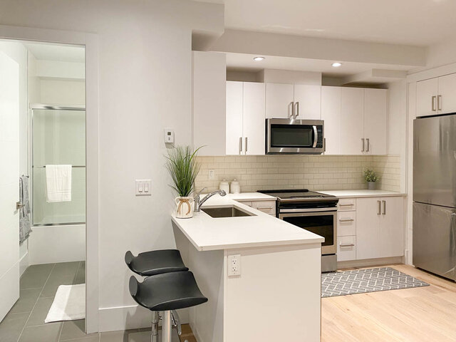 Bright kitchen with white island countertop and stainless steel appliances. - Suite - 2825 Edgemont Blvd, North Vancouver
