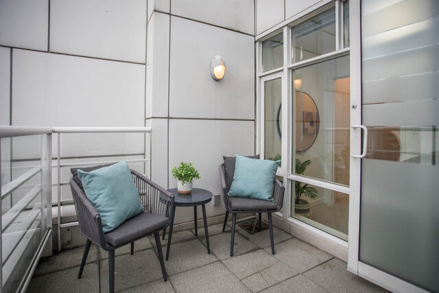 Furnished balcony with modern chairs, teal cushions, and a small potted plant. - THA - 1199 Marinaside Cres, Vancouver Downtown