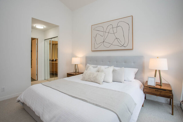 Spacious bedroom with a tufted headboard, modern artwork, and sleek nightstands. - THA - 1199 Marinaside Cres, Vancouver Downtown