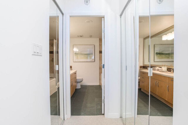 Spacious bathroom with modern vanity and large mirror, featuring neutral tones and a serene artwork. - THA - 1199 Marinaside Cres, Vancouver Downtown