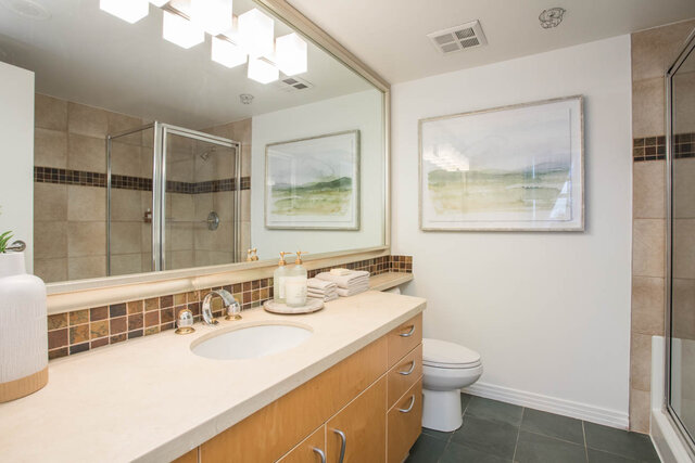 Spacious bathroom with dual sinks, large mirror, and framed artwork. - THA - 1199 Marinaside Cres, Vancouver Downtown