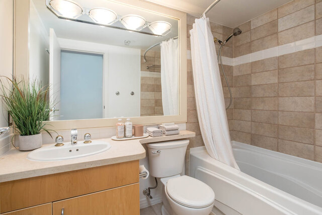 Spacious bathroom with light wood cabinets, a large mirror, and a bathtub/shower combo. - THA - 1199 Marinaside Cres, Vancouver Downtown