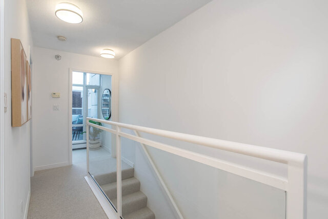 Staircase leading to upper level with white railings and carpeted steps. - THA - 1199 Marinaside Cres, Vancouver Downtown