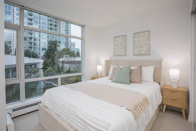 Spacious bedroom with large windows offering a city view and modern decor. - THA - 1199 Marinaside Cres, Vancouver Downtown