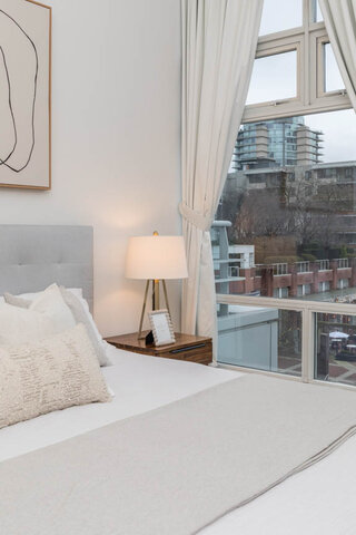 Spacious bedroom with a cozy bed, wooden nightstand, and a city view. - THA - 1199 Marinaside Cres, Vancouver Downtown