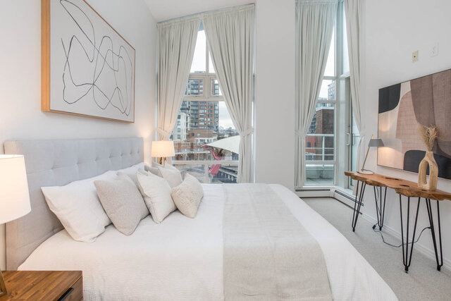 Spacious bedroom with a large bed, white bedding, and a city view through tall windows. - THA - 1199 Marinaside Cres, Vancouver Downtown