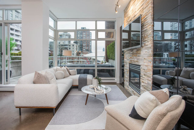 Spacious living room with modern furniture, a stone fireplace, and a large window offering a city view.
