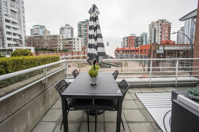 Spacious rooftop patio with a black and white striped umbrella, modern furniture, and a stunning city view.