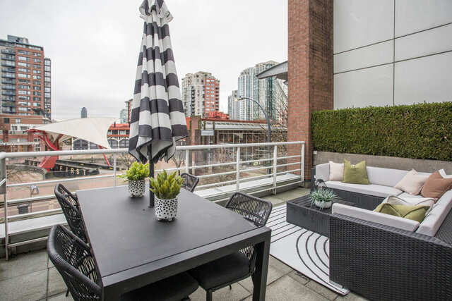 Spacious rooftop patio with modern furniture, city view, and striped umbrella. - THA - 1199 Marinaside Cres, Vancouver Downtown